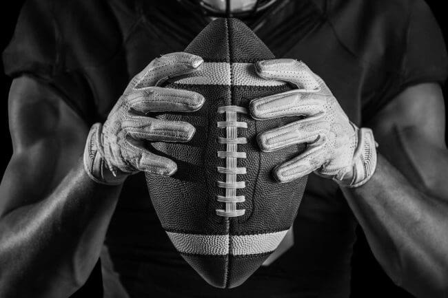Close-up of a football player holding a ball, symbolizing focus and strategy akin to the services provided by a professional SEO agency.
