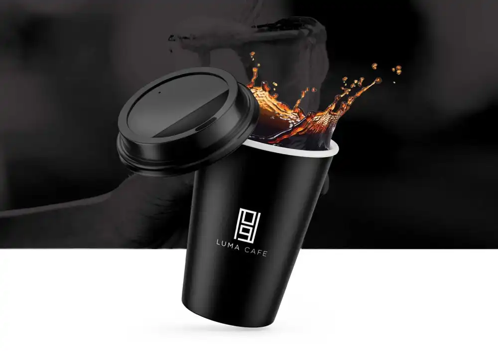 A stylish black coffee cup with a lid, branded with the logo of LUMA, is shown with coffee splashing out.