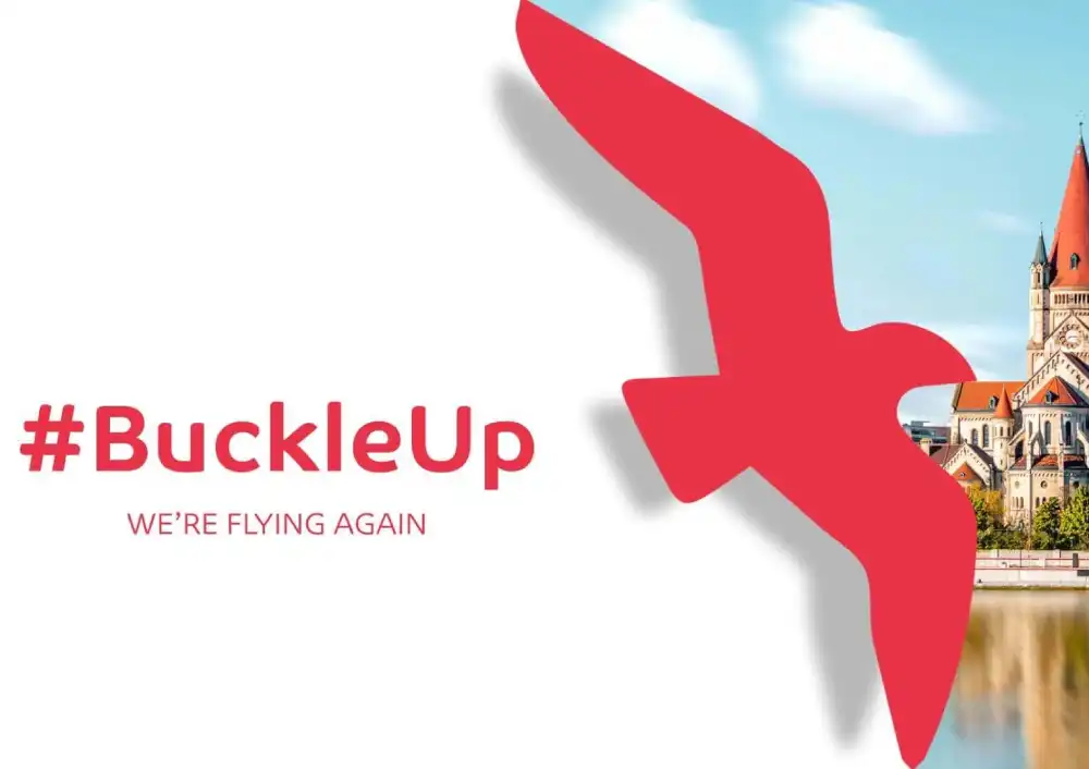 شعار العربية للطيران و طيران العربية مع عبارة #BuckleUp على خلفية سماء زرقاء ومبنى.