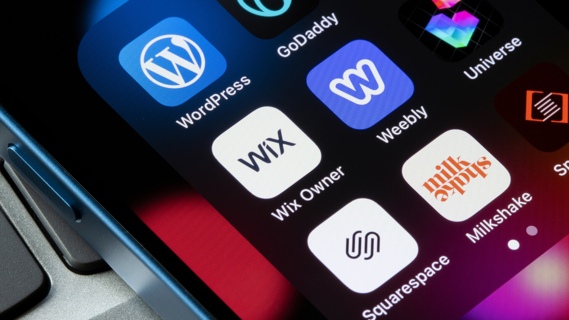 A smartphone screen displaying various website design and development apps such as WordPress, Wix, GoDaddy, Weebly, Squarespace, and Milkshake. These tools are commonly used for website design, website SEO marketing, and creating creative designs. They support businesses in implementing marketing website designs and formulating effective business strategies for online presence.